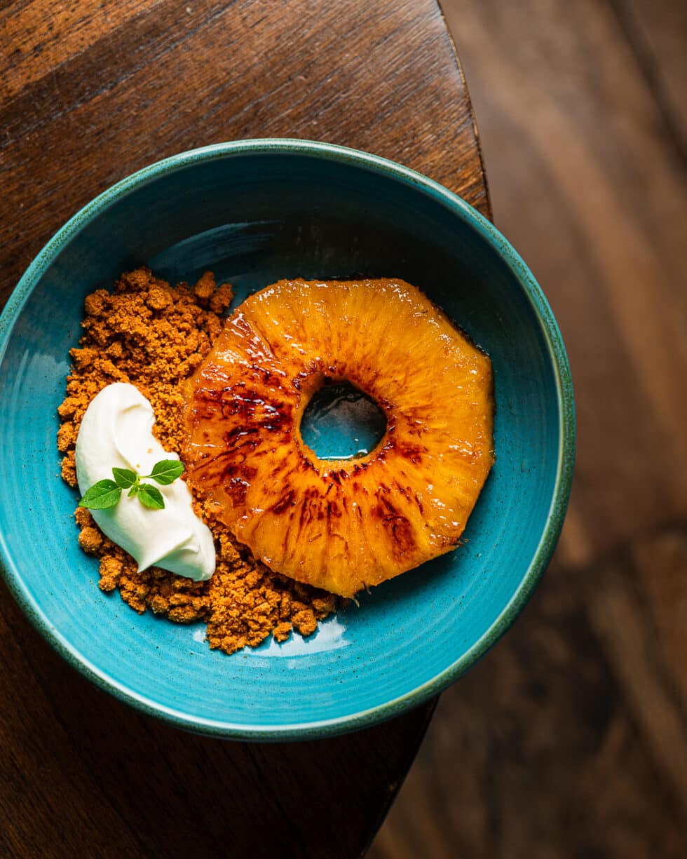 Ananas grillé avec crumble et crème sur assiette bleue