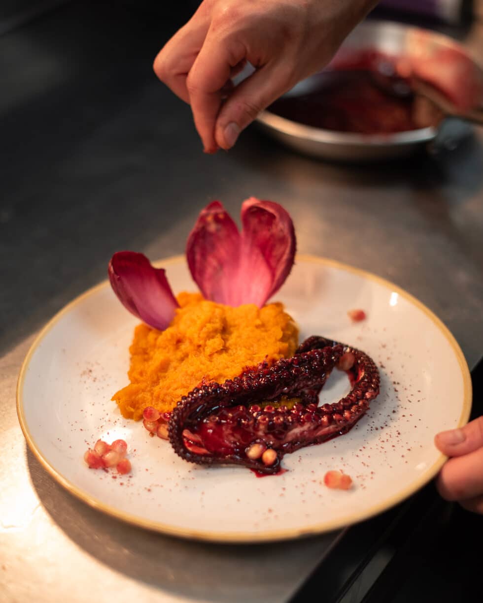 Chef assaisonnant poulpe grillé, purée de carotte