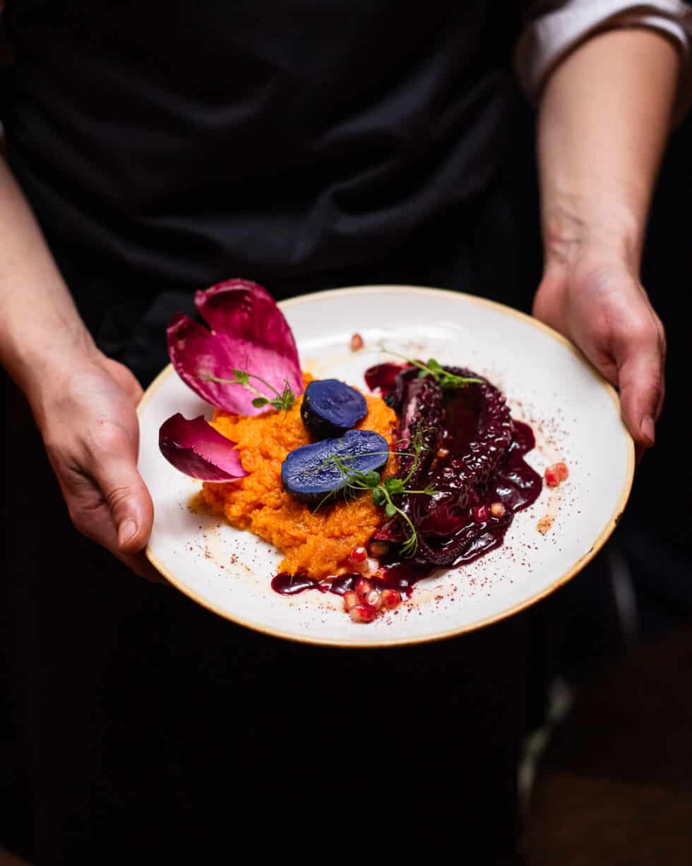 Serveur présentant une assiette de plats colorés