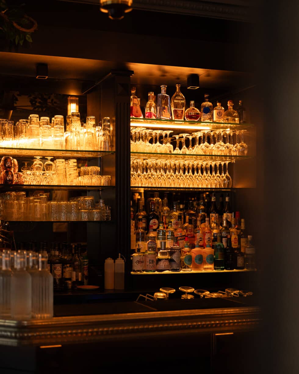 Bar élégant avec étagères lumineuses de bouteilles et verres